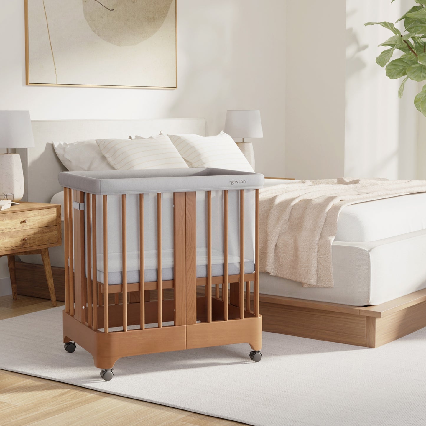 Chestnut color Newton Nest Convertible Crib in bassinet setting next to bed in bedroom