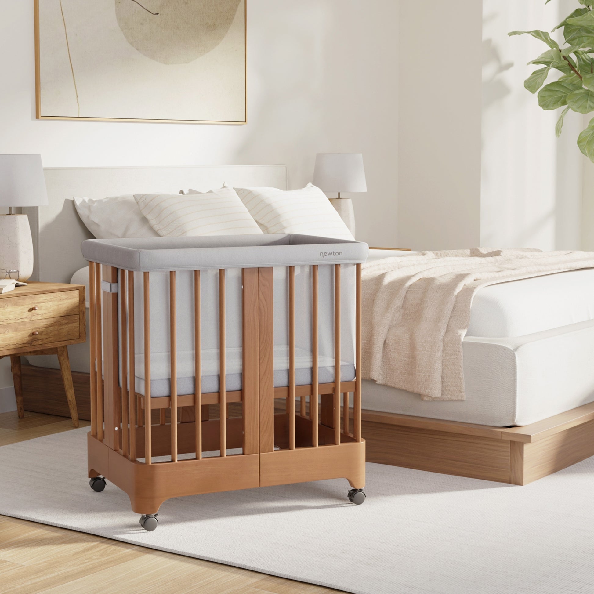 Chestnut color Newton Nest Convertible Crib in bassinet setting next to bed in bedroom