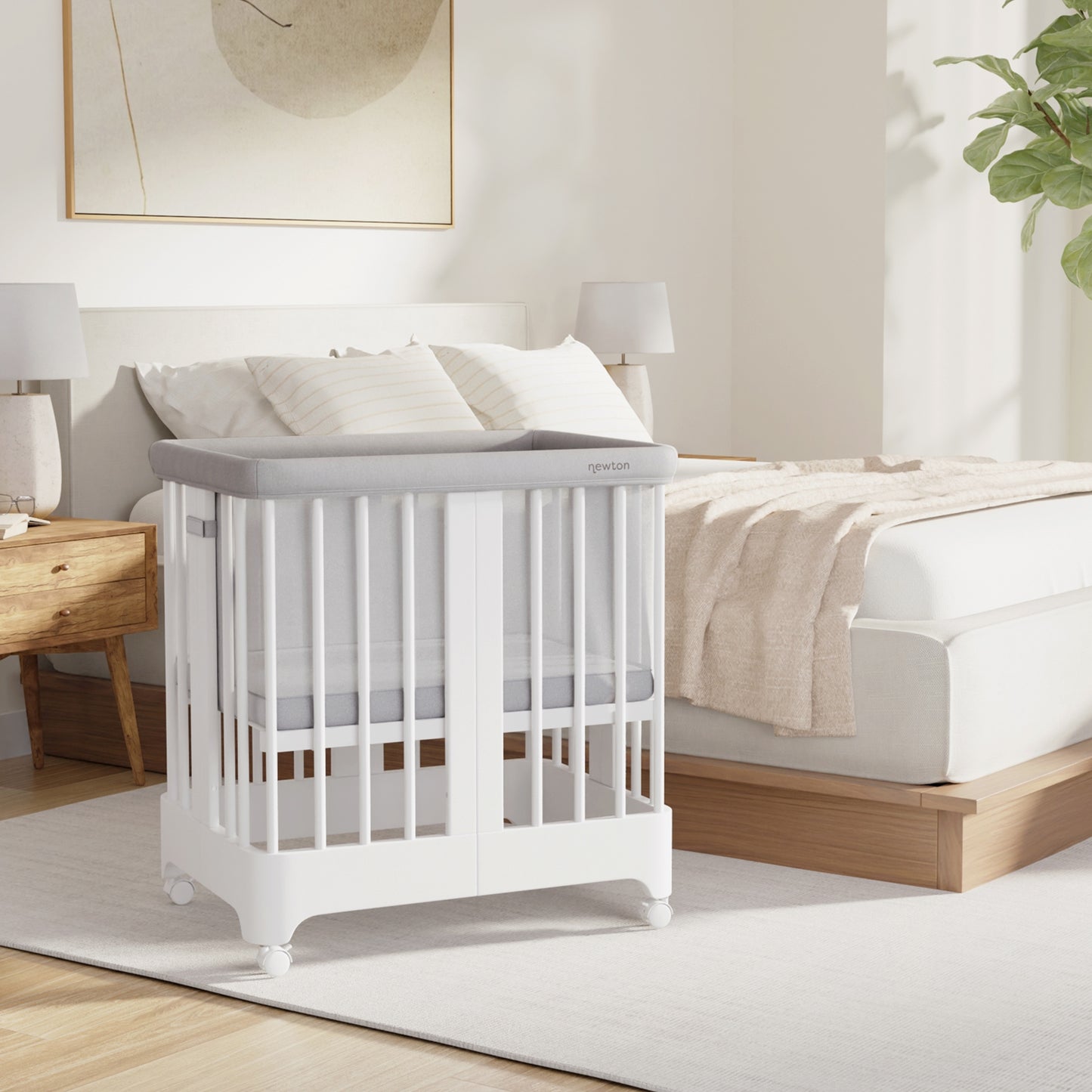 White color Newton Nest Convertible Crib in bassinet setting next to bed in bedroom