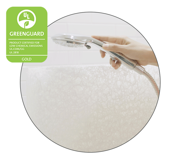A person holds a shower head, rinsing a Newton mattress in a bathtub.