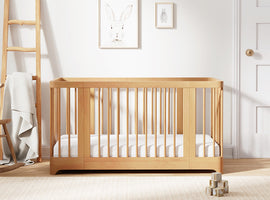 Wooden crib in a room with white walls and a ladder.