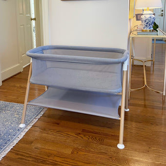 Gray essential bassinet in neutral room with blue rug