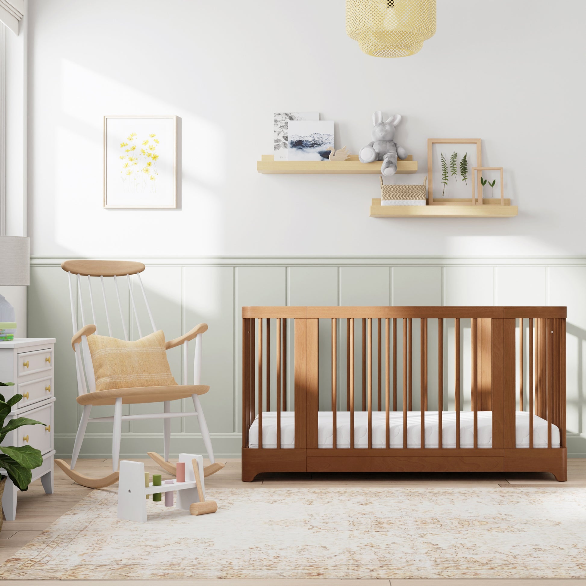 Chestnut color Newton Nest Convertible Crib in crib setting, in nursery next to rocking chair