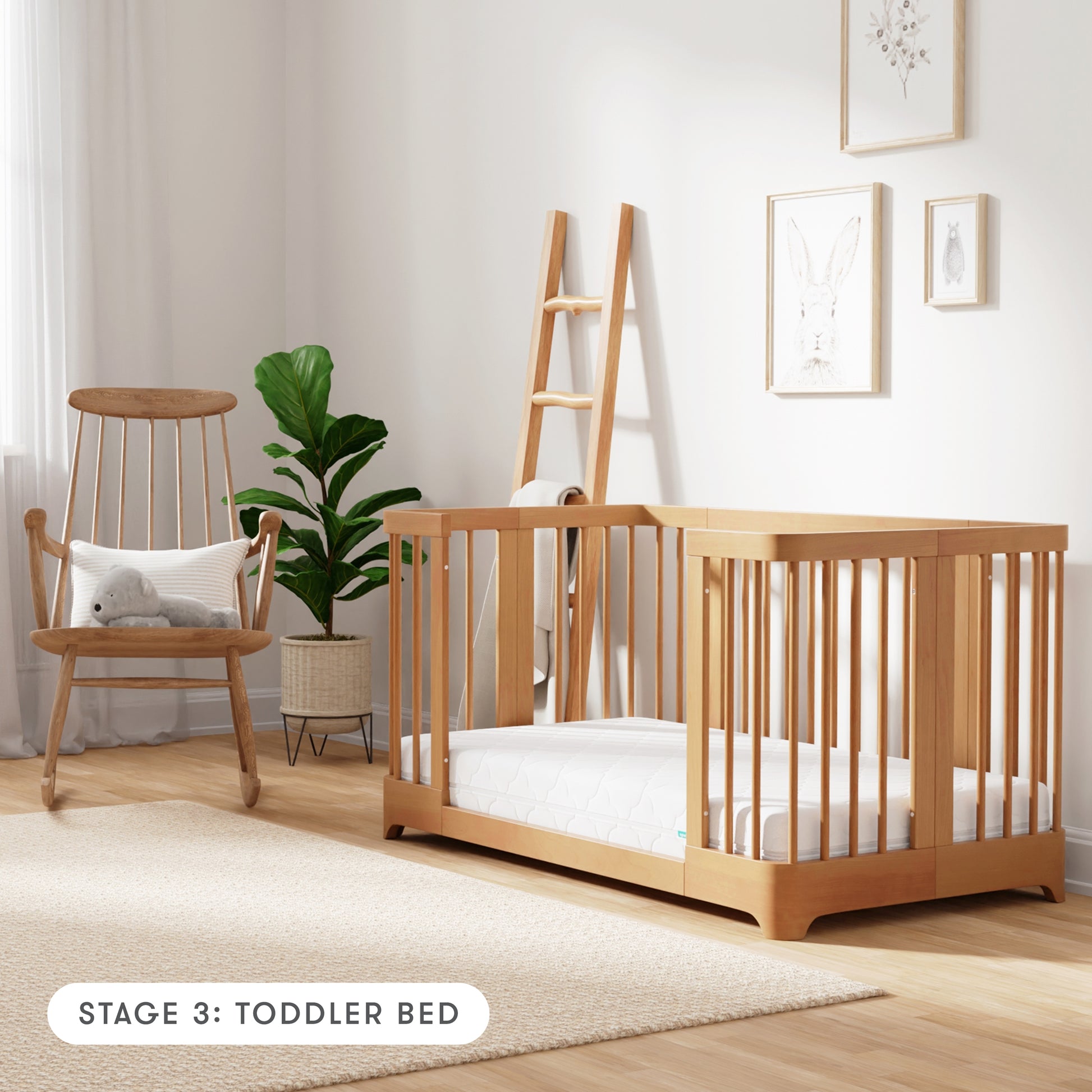 Natural color Newton Nest Convertible Crib in toddler bed setting, in nursery next to rocking chair, with text "Stage 3: Toddler Bed"