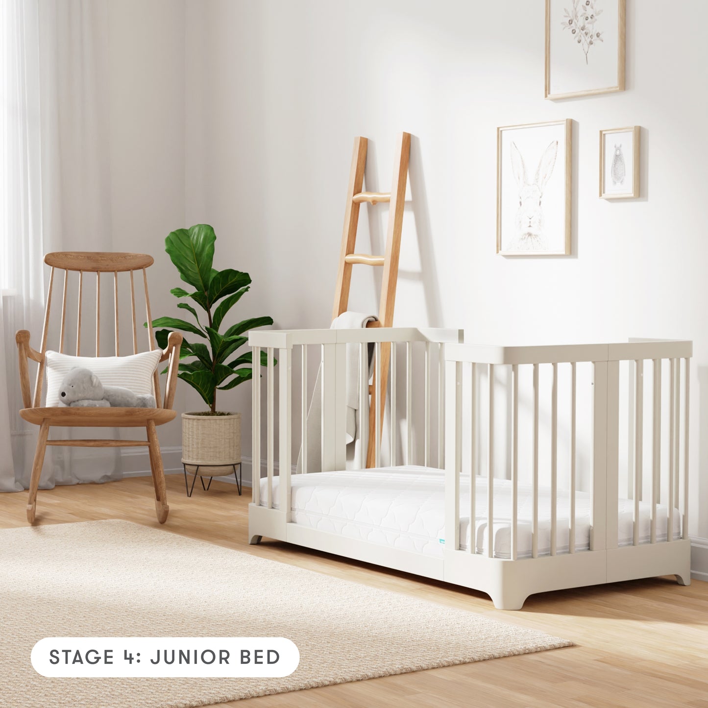 warm white color Newton Nest Convertible Crib in Junior Bed setting, in nursery next to rocking chair, with text "Stage 4: Junior Bed"