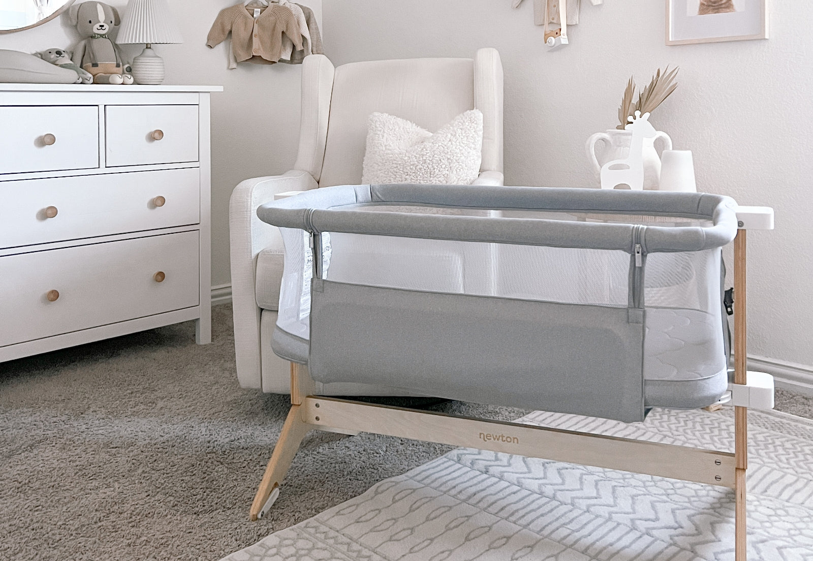 A serene nursery featuring a grey Newton baby crib in a well-organized room with neutral-toned decor.
