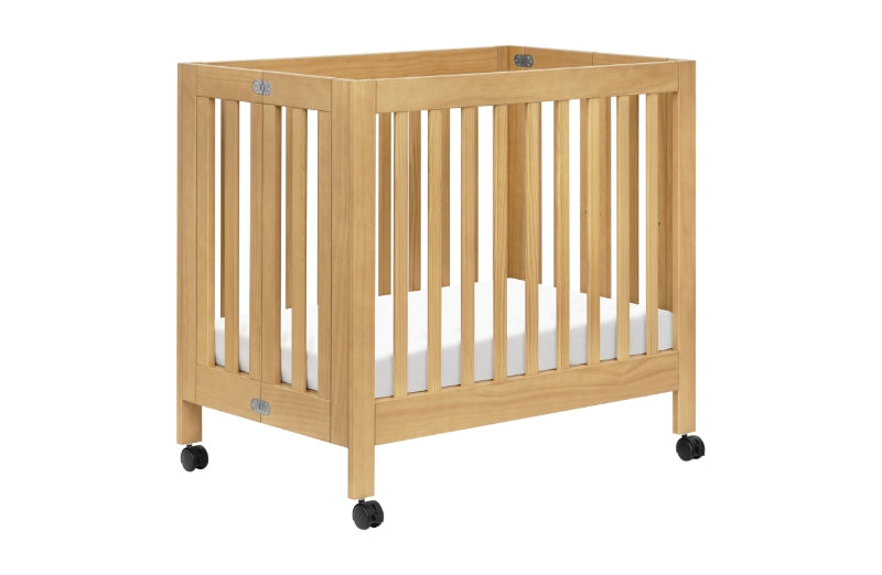 Wooden baby crib on wheels with vertical slats and a white mattress, isolated on a white background.