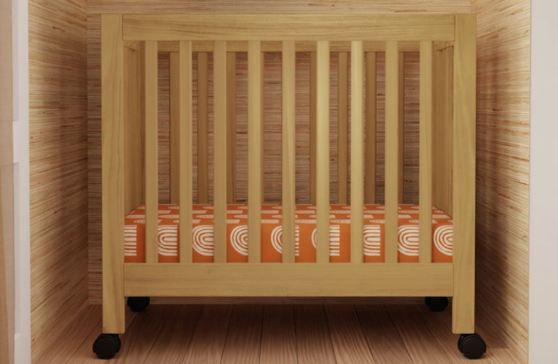 Wooden crib with a patterned mattress in a room with wood paneled walls. 999-8505-HNY