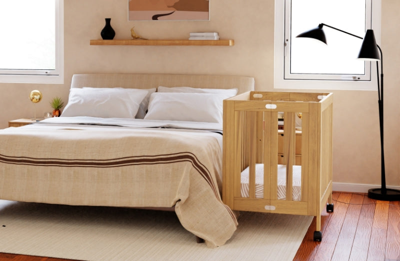 A stylish modern bedroom featuring a large bed with beige linens and a wooden baby crib by the window.