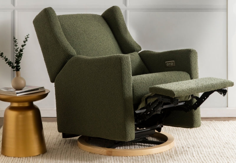 A plush green nursery rocking chair with footrest extended, positioned next to a small gold side table and a decorative plant, enhancing a tranquil reading nook.