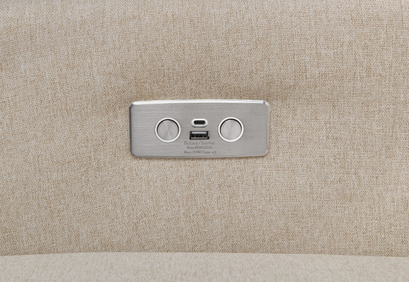 A close-up of a metallic dual USB charging port embedded in a beige fabric surface, labeled "Output 5V=2.1A Max/5V=1A."