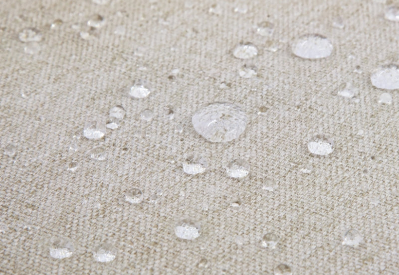 Close-up of water droplets on a textured beige fabric, demonstrating water resistance.