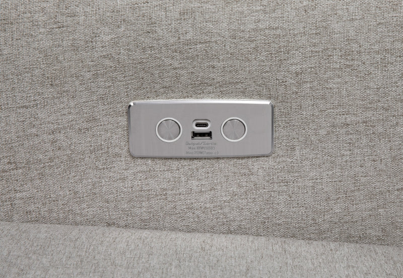 Close-up of a USB charging port on a gray fabric surface, marked with a USB symbol and power symbol.