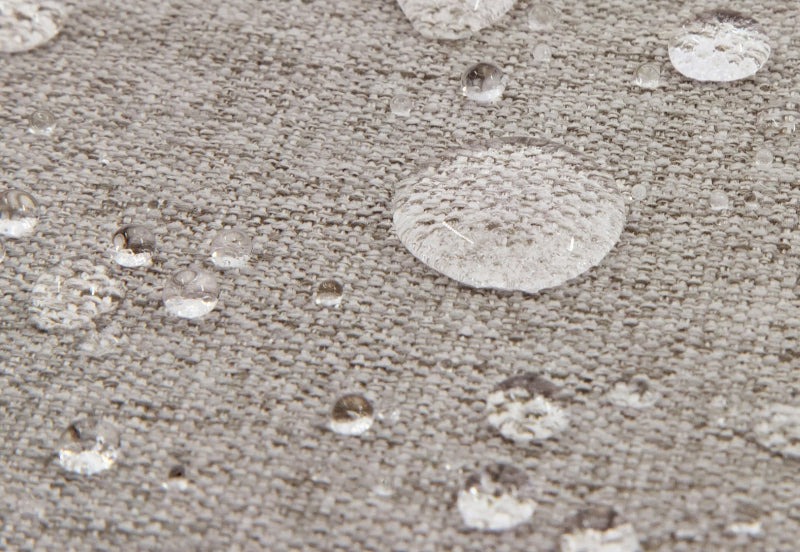 Close-up view of water droplets on a gray textured fabric, demonstrating water resistance.