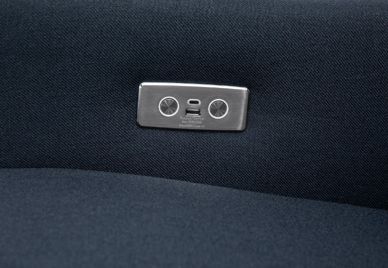 Close-up of a metallic seat adjustment button on a dark fabric car seat.