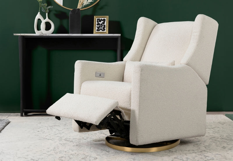 Modern cream-colored nursery glider with extended footrest in a stylish room with dark green walls and a decorative table.