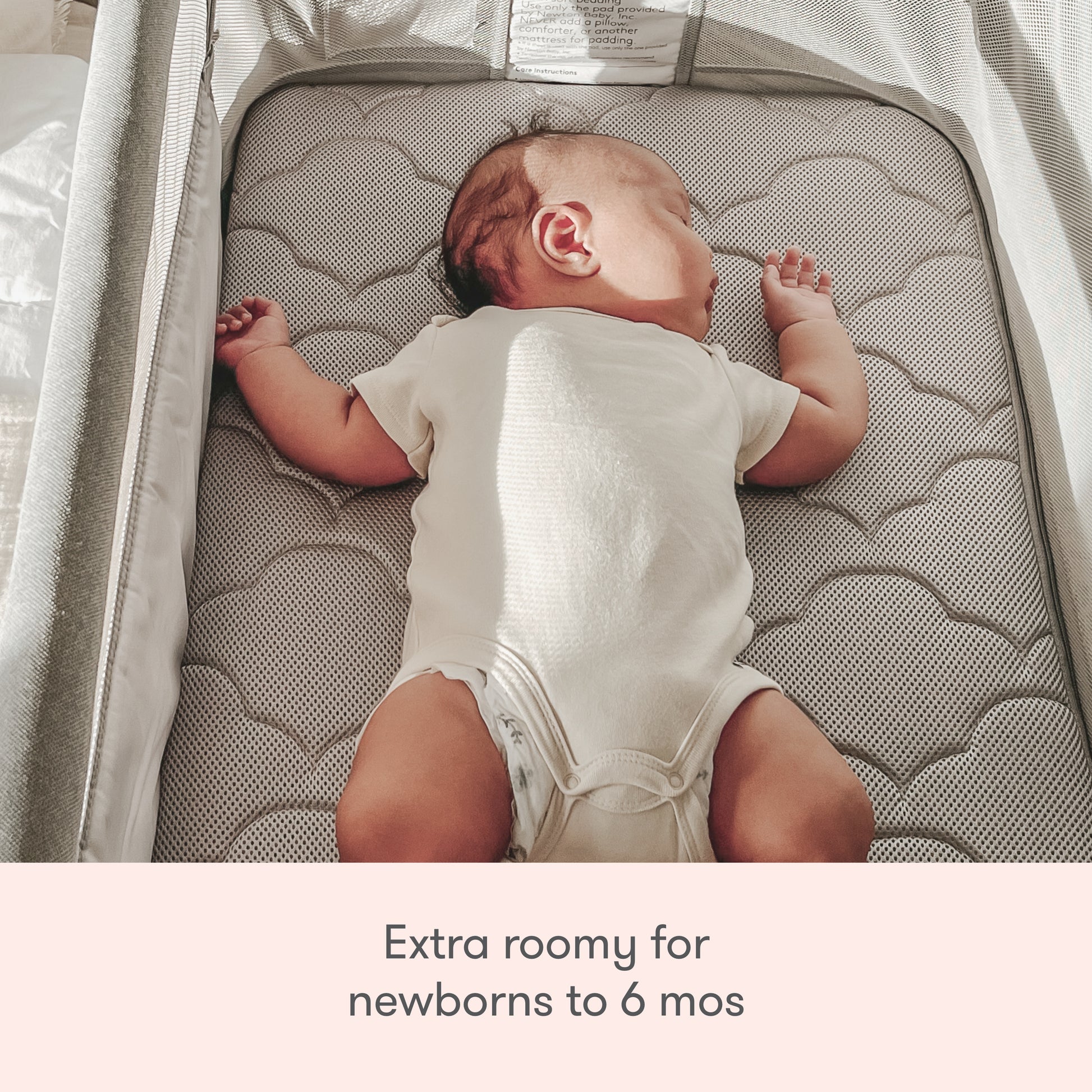 A baby sleeps on its back in the spacious Newton Baby Bassinet & Bedside Sleeper with a cloud-patterned Wovenaire mattress. Text below reads: “Extra roomy for newborns to 6 mos.”.