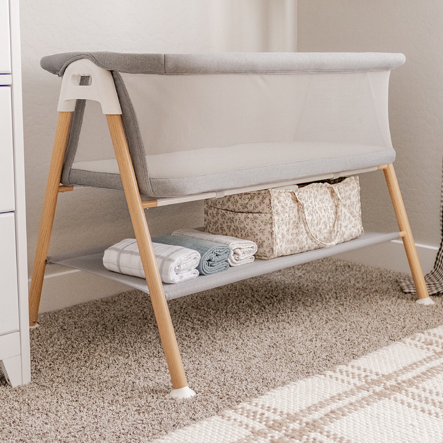 essential bassinet in nursery, storage space below cradle filled with baby care essentials