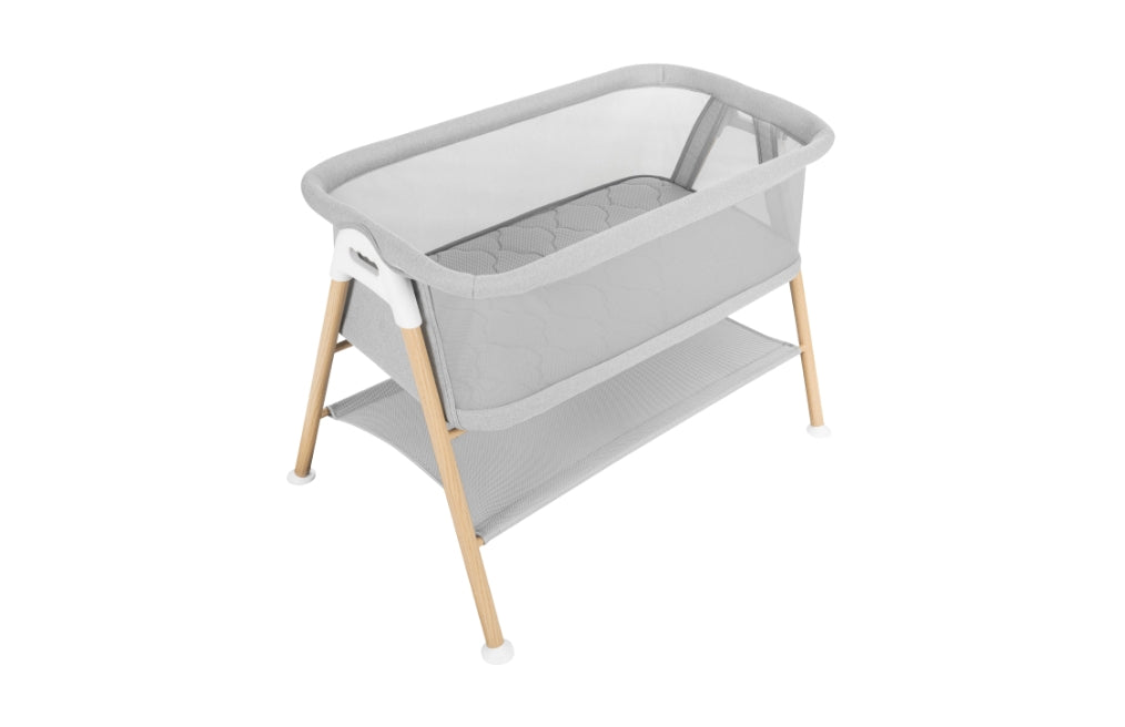 Essential Bassinet with grey fabric, a breathe-thru mesh walls, faux-wood finish on metal legs, and a storage shelf. Wovenaire® mattress included.
