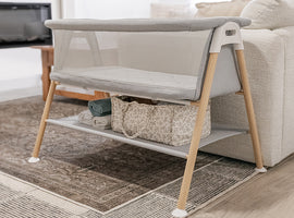 Portable crib with wooden legs in a living room setting