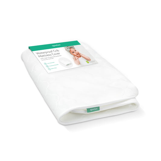 A folded white Newton Baby Extra Waterproof Crib Mattress Cover in its packaging, with a green label showing product info and a baby image. The label notes breathability, water resistance, and softness.