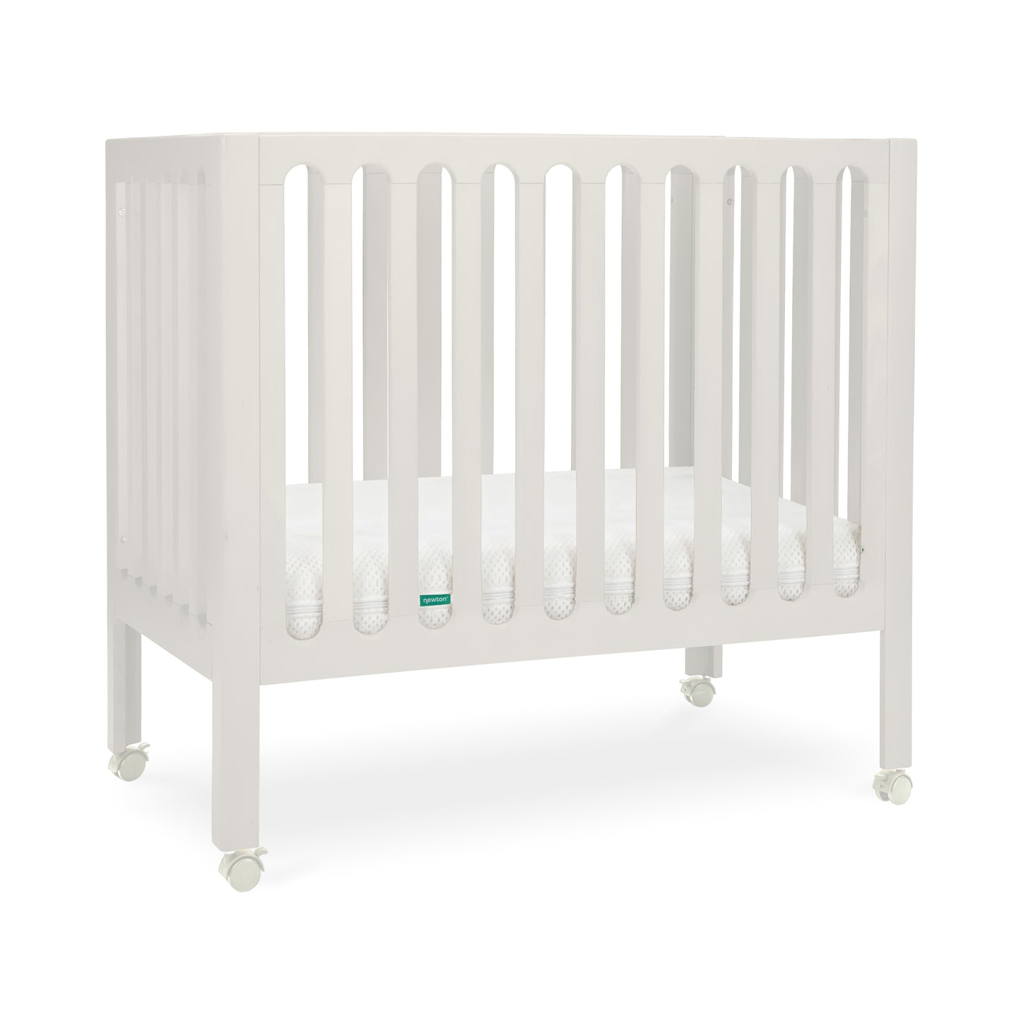 newton warm white crib with mattress inside and wheels on white background.