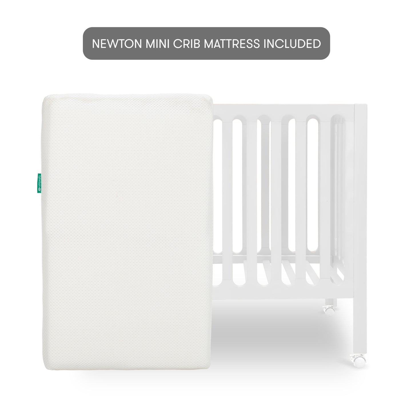 White modern crib on wheels with mattress leaned against crib, isolated on a plain background. With text "newton mini crib mattress included"