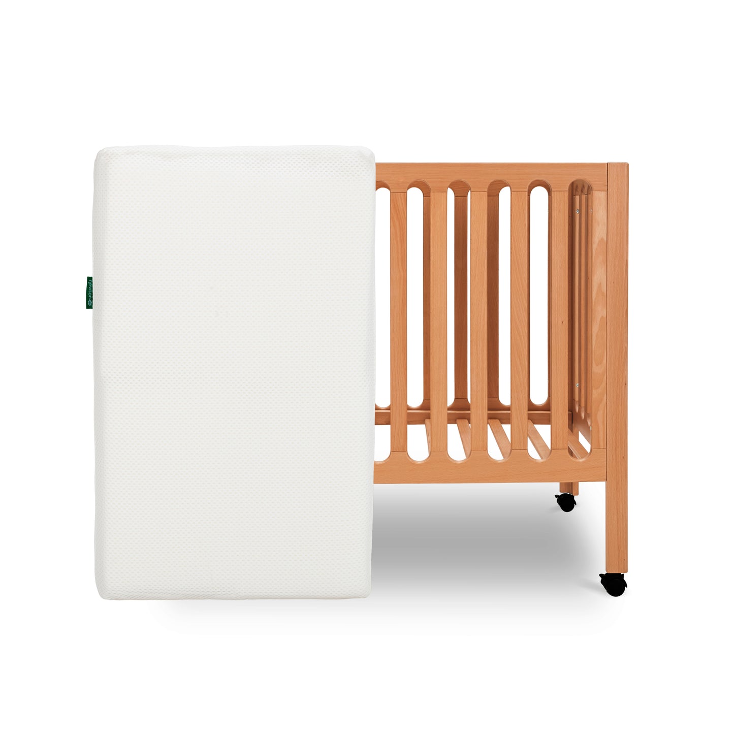 Modern wooden crib on wheels with mattress leaned against crib, isolated on a white background.