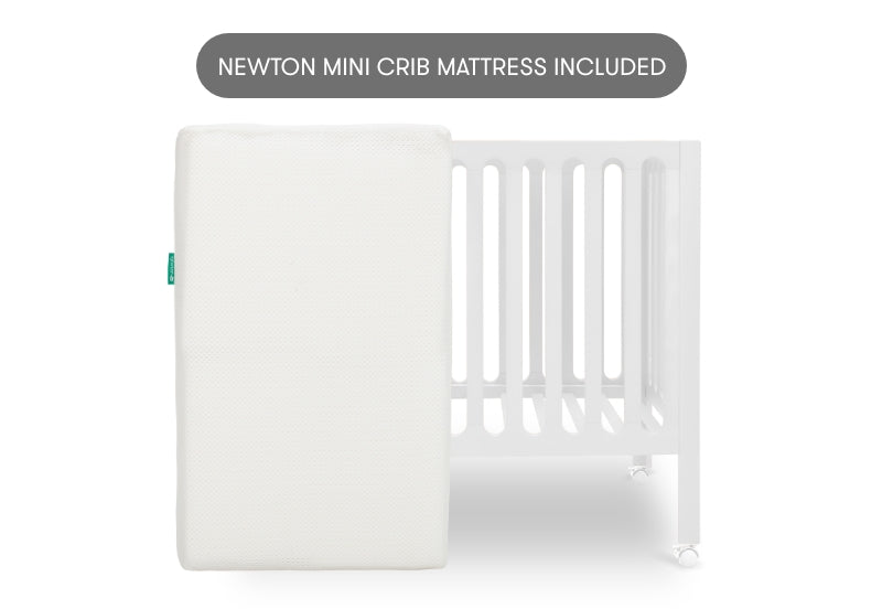 White crib mattress by a crib with slatted sides on a white background. With text "newton crib mattress included"