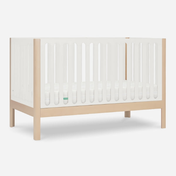 The Newton Galileo Convertible Crib by Newton Baby features natural beech wood legs and white slatted sides, displayed against a plain white background.
