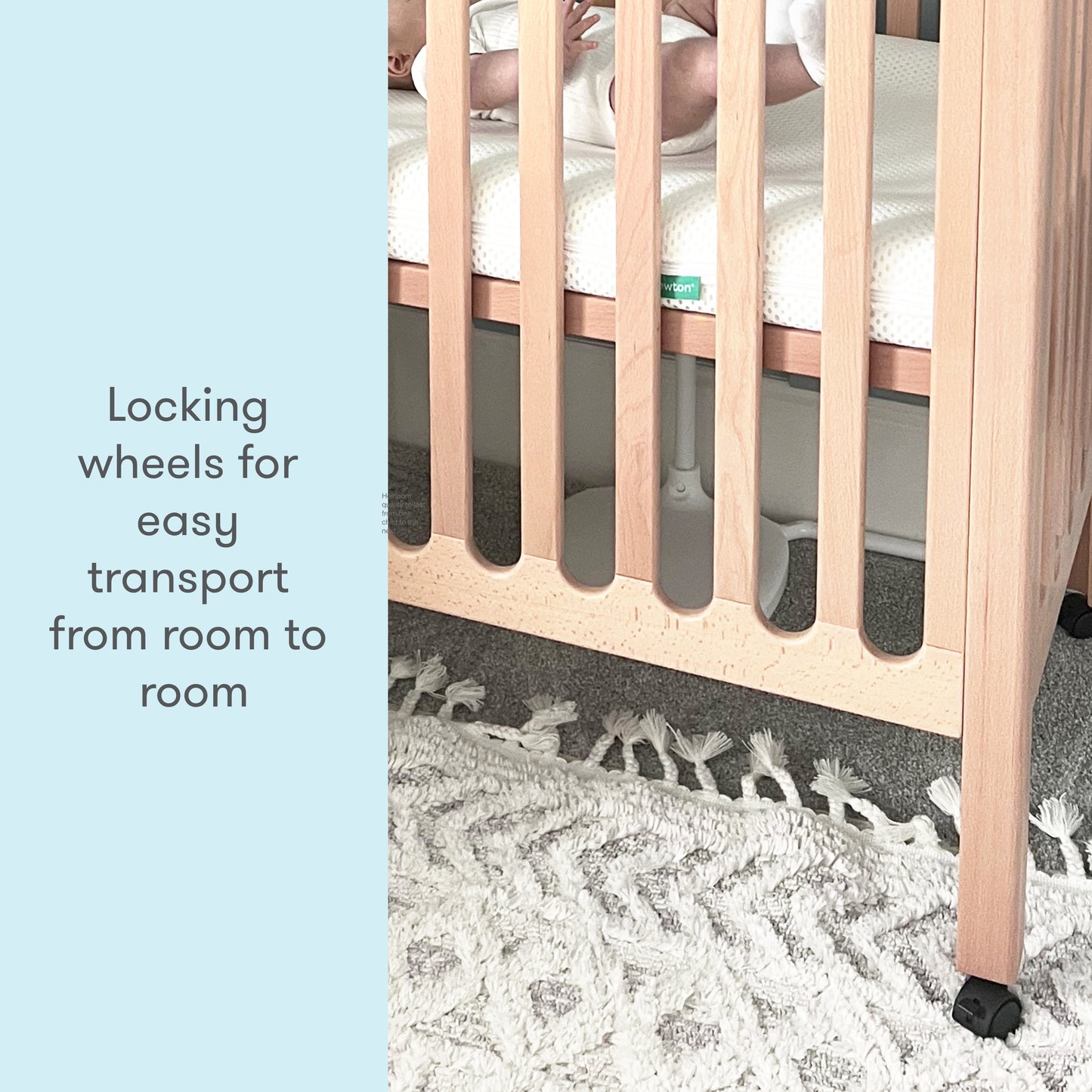 Wooden baby crib with locking wheels, displayed on a patterned carpet with the text "Locking wheels for easy transport from room to room."