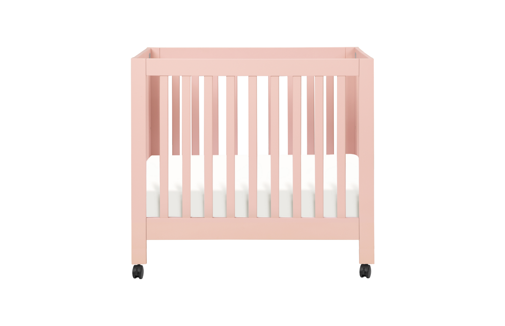 The Babyletto Origami Mini Crib is a stylish pink portable crib with slatted sides, white mattress, and four black wheels—ideal for small spaces, shown on a plain white background.