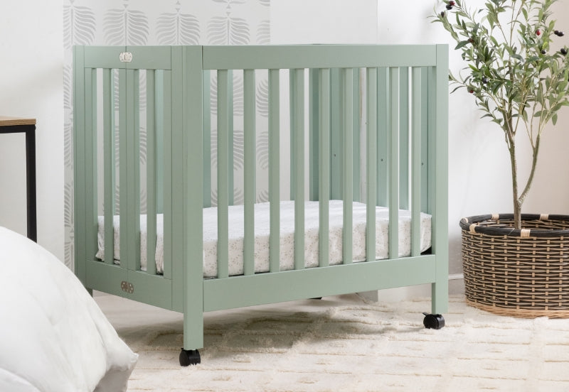 A serene nursery scene featuring a mint green crib labeled with the logo "crib" set against a neat, plant-accented background.