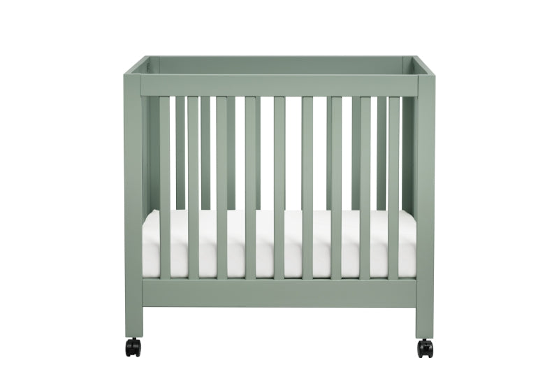 Modern sage green baby crib on wheels with a white mattress.