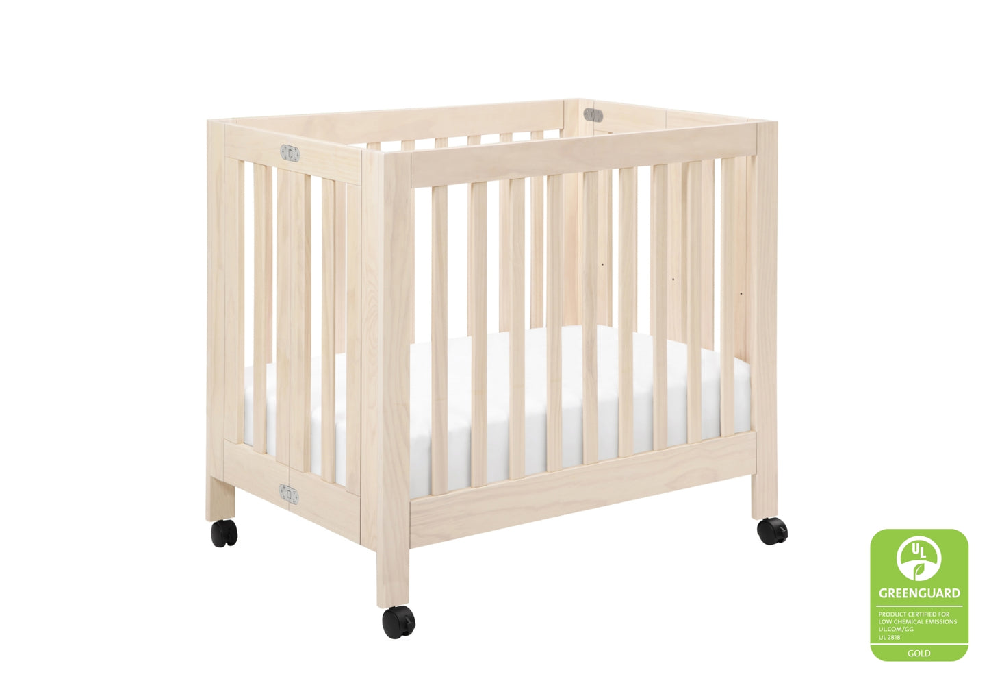 Wooden baby crib on wheels with a white mattress, featuring a green "GREENGUARD GOLD" certification badge.