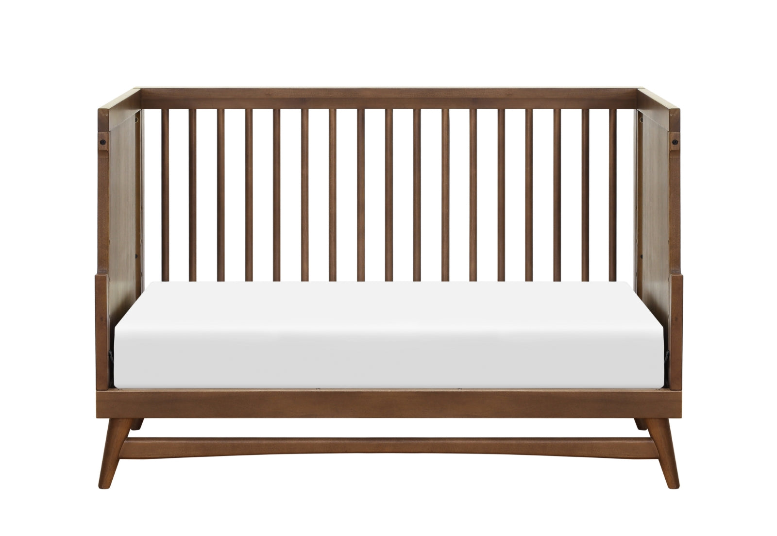 The Babyletto Peggy Convertible Crib, crafted from solid New Zealand pine wood with vertical slats and angled legs in a mid-century modern style, is shown with a white mattress against a plain white background—ideal for a modern nursery.