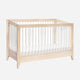 The Babyletto Sprout Convertible Crib features a simple, modern design with a light wood frame, white vertical slats, and a white mattress, making it an ideal 4-in-1 nursery piece for any space.