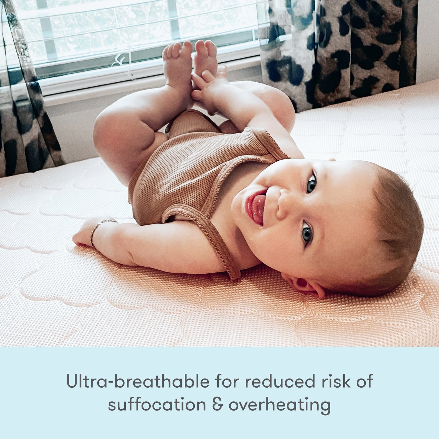 Image of a baby wearing a cute outfit, lying on a mattress, with text stating "Ultra breathable for reduced risk of suffocation & overheating."
