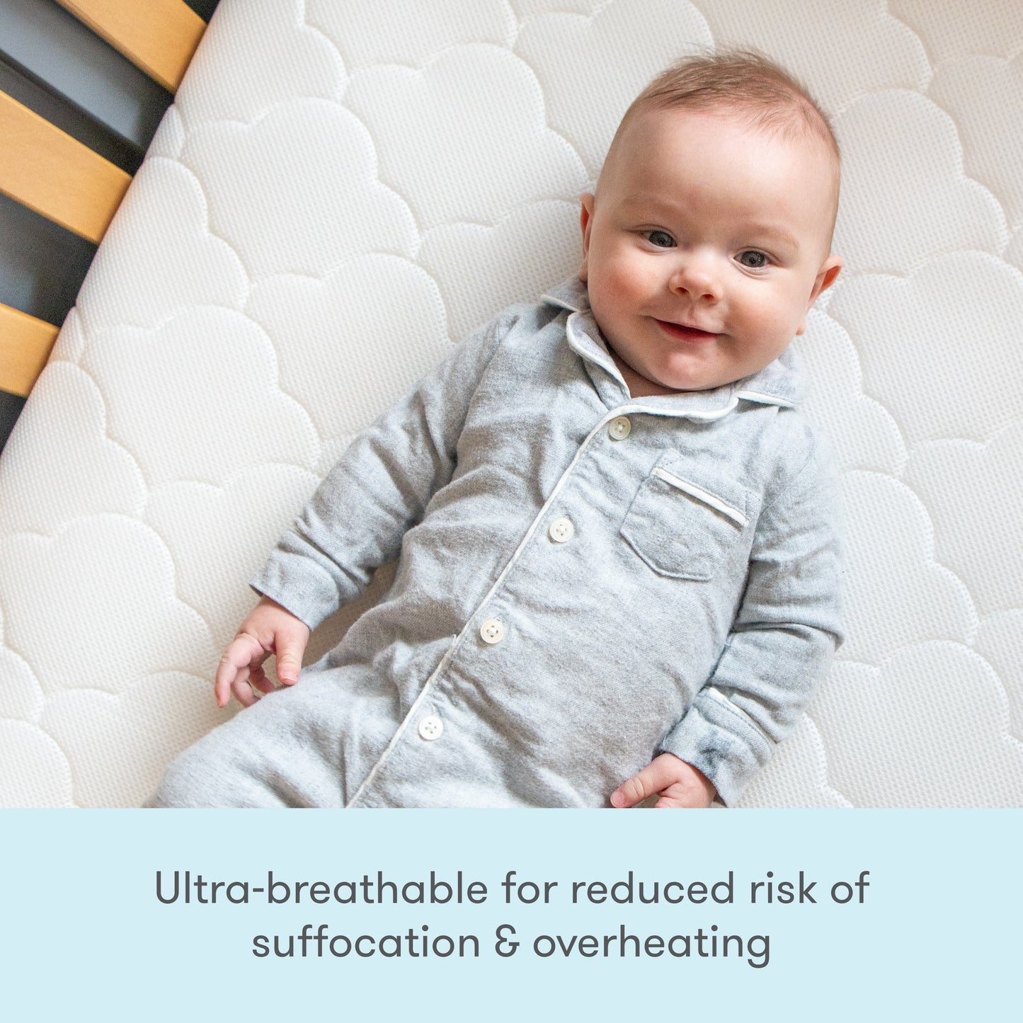 Image of a baby wearing a cute outfit, lying on a mattress, with text stating "Ultra breathable for reduced risk of suffocation & overheating."