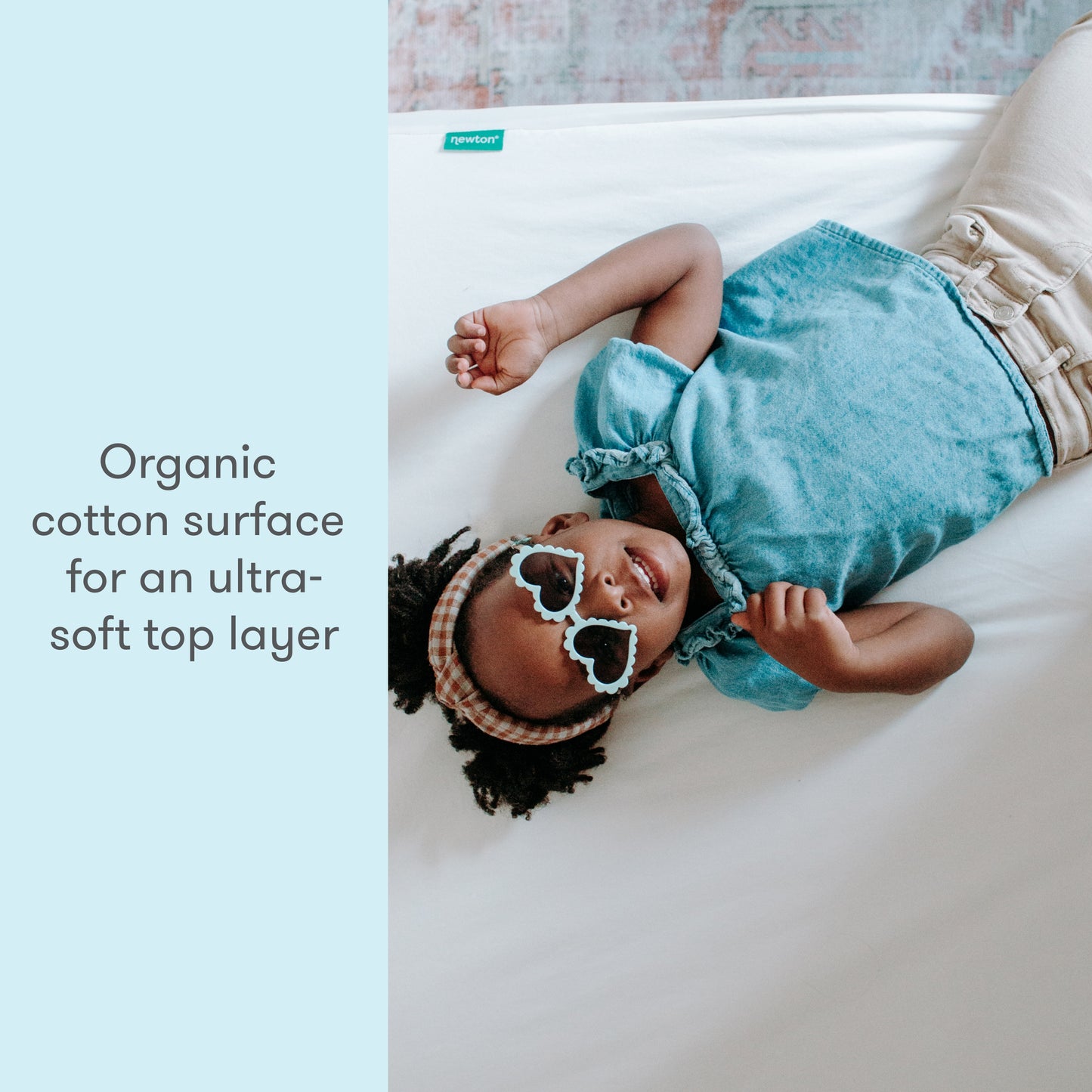 image of a child wearing sunglasses lying on a bed with text "organic cotton surface for an ultra soft top layer"