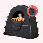 baby sitting in crib, underneath black slumberpod blackout tent, with fan icon