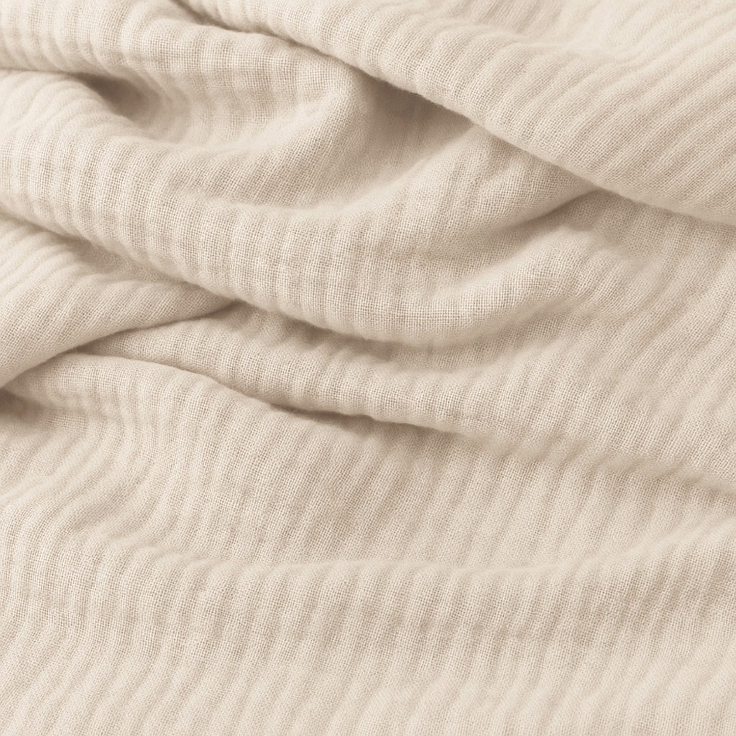 Close-up of soft, beige ribbed fabric with gentle folds and subtle textured lines, ideal for Newton Baby Compact Travel Crib Sheets—perfect for a snug fit and breathable feel.