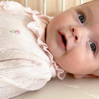 A smiling baby lying in a crib, radiating joy and innocence.