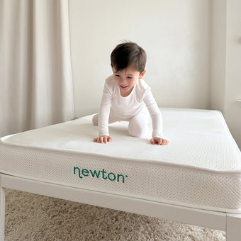 A baby crawling on a soft newton mattress, exploring their surroundings with curiosity and delight.