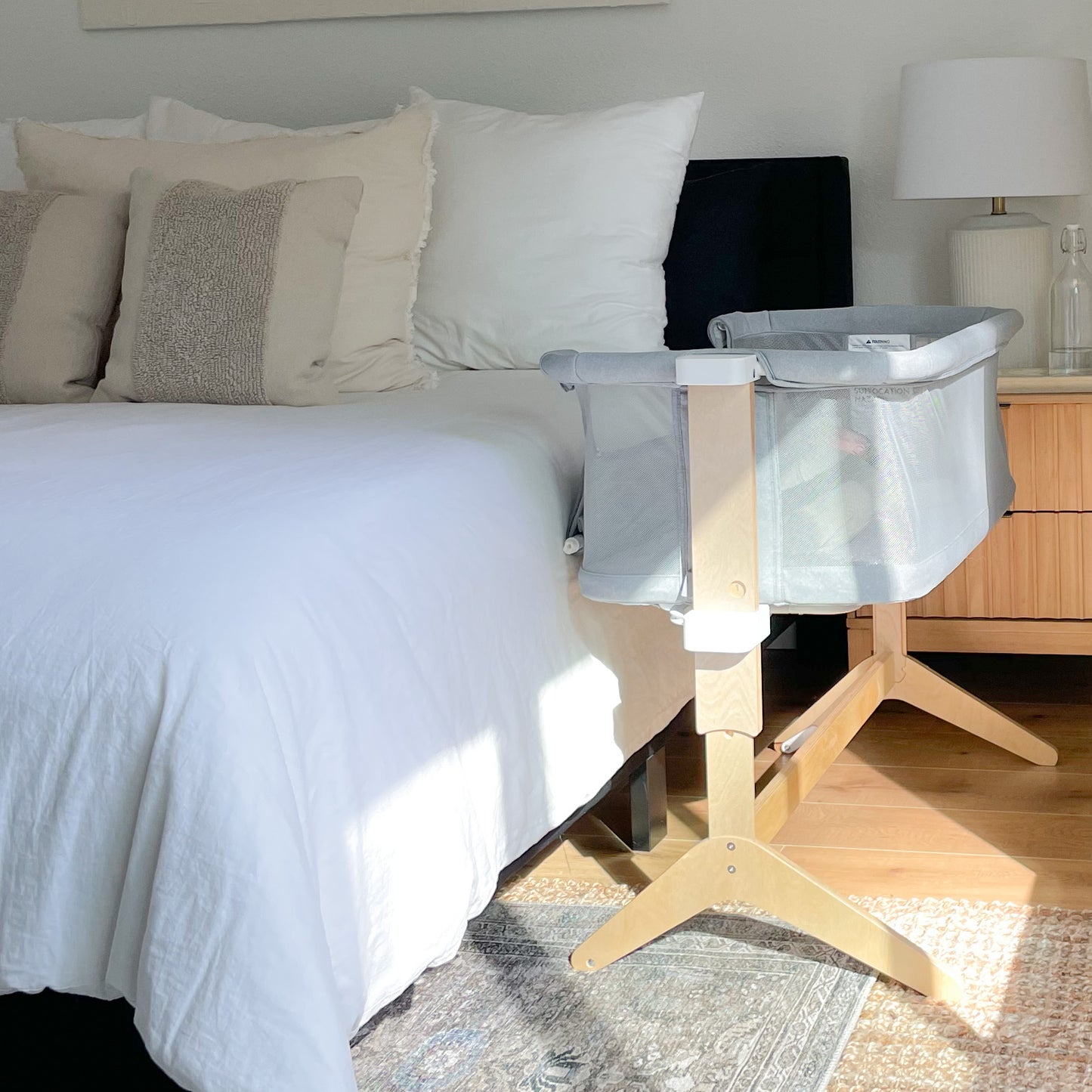 Skip- Bedside sleeper in grey with wood legs in a neutral bedroom attached to the bed.