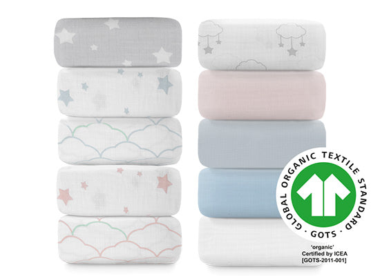 A stack of assorted sheets in various pastel colors and patterns, including stars and clouds, certified by GOTS and USB TEX5453.