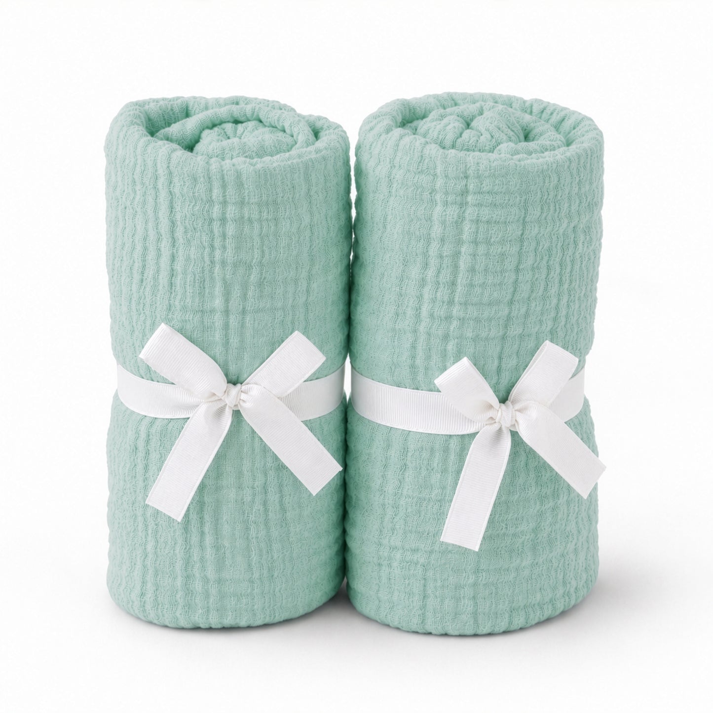 Two rolled, mint green Newton Baby Breathable, Organic Cotton Sheets (2-pack) stand upright side by side, each tied with a white ribbon around the middle, shown on a plain white background.