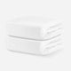 Two neatly stacked white cotton baby blankets on a solid white background. skip