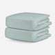 Two folded pale green, breathable baby crib sheets displayed on a neutral background. skip