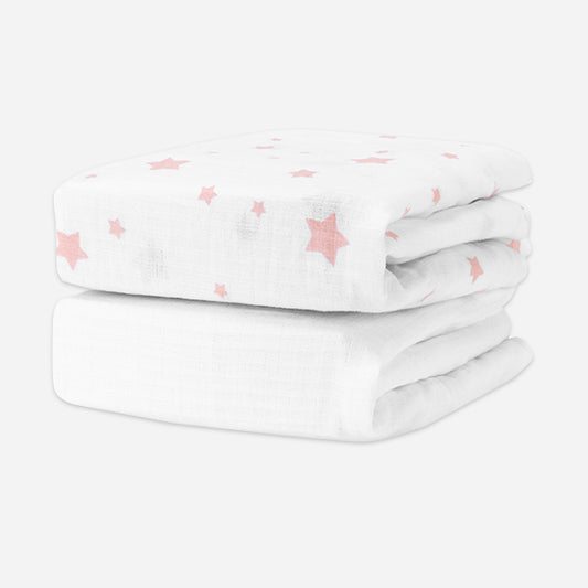 Two folded crib sheets, one white with pink stars and one solid white, stacked on a white background. skip